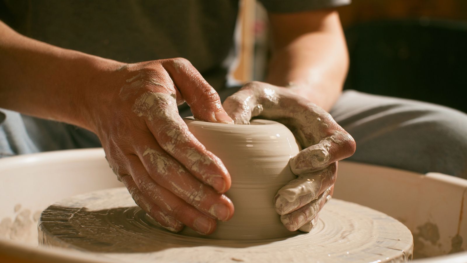 Close up of the hands of a potter shaping a piece